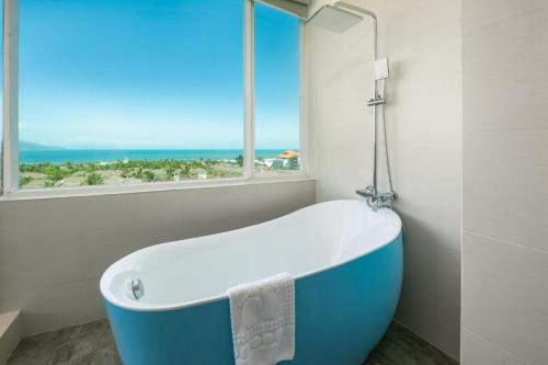 a bath tub in a bathroom with a window at Fansipan Da Nang Hotel in Da Nang