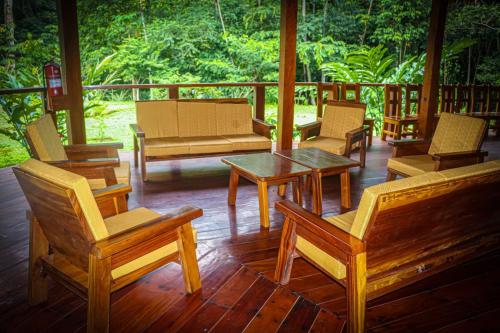 porche con sillas de madera, mesa y sillas en Kotsimba Lodge, en Puerto Leguía