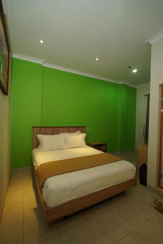 a bedroom with a green wall and a bed at The Cabin Hotel Ngupasan in Yogyakarta