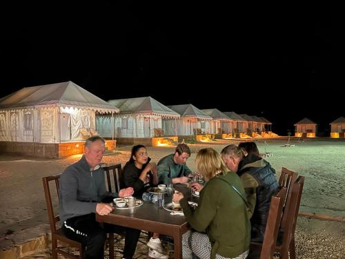 a group of people sitting at a table eating food at Heritage Luxury Camp in Sām
