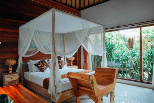 - une chambre avec un lit à baldaquin et une chaise dans l'établissement Way Ubud House, à Ubud