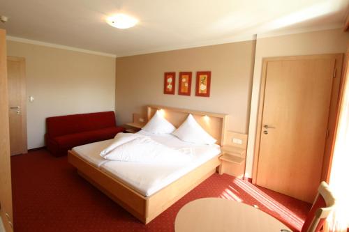 a hotel room with a bed and a red couch at Frühstückshotel Margret in Maurach
