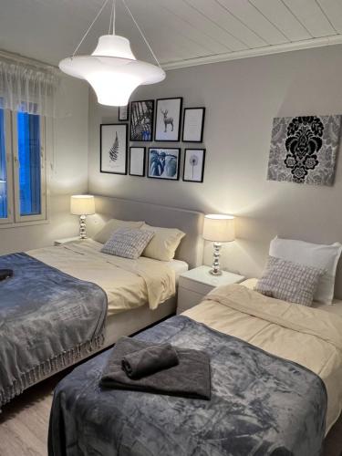 two beds in a room with two lamps and pictures on the wall at Villa Aurora View in Rovaniemi