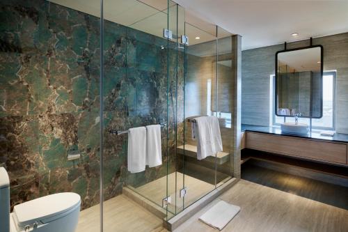 y baño con ducha de cristal y aseo. en VIVERE Hotel, ARTOTEL Curated, en Tangerang