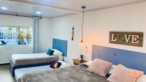 a bedroom with two beds and a love sign on the wall at Be Happy Hotel in San Andrés