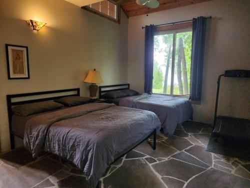 a bedroom with two beds and a window at Waterfront Cottage in Lion's Head in Stokes Bay