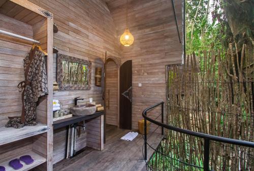 a bathroom with wooden walls and a tree at Sacred Beji by GenuineHost in Payangan