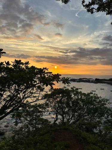 a sunset over the water with trees in the foreground at Casa Zion in San Juanillo