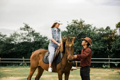 a woman riding a horse next to a man at Gachilly House - Your Cozy Home In The Heart Of The BMT City in Buon Ma Thuot