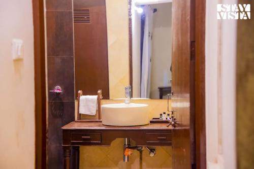 ein Bad mit einem Waschbecken und einem Spiegel in der Unterkunft StayVista's Rustic Respite - Hillside Retreat near Tala Gate with Swimming Pool, Lawn & Indoor-Outdoor Games in Tāla
