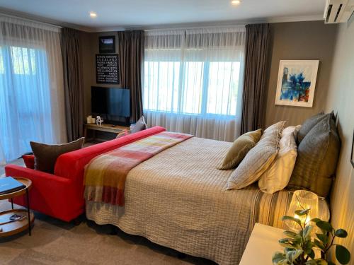 a bedroom with a large bed and a red chair at Escape in New Plymouth