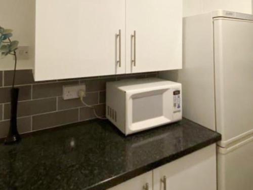 a kitchen counter with a microwave and white cabinets at Normanton in Birmingham