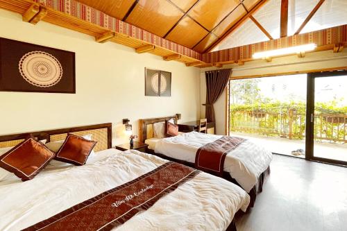 two beds in a room with a large window at Vân Hồ Ecolodge in Mộc Châu