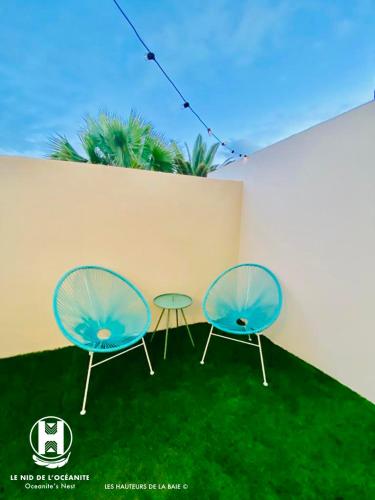 two blue chairs and a table on the grass at Les Hauteurs de la Baie in Noumea
