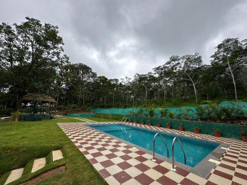 a swimming pool in a yard with a checkered sidx sidx sidx at The Mallika Holidays in Mananthavady