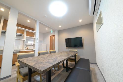 a dining room with a table and chairs and a tv at 和ノ楓cottage　新宿の2階建て5室2シャワー2トイレ in Tokyo
