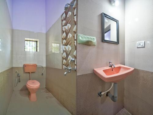 ein Badezimmer mit einem rosa Waschbecken und einem WC in der Unterkunft Dolphin service apptment in Calangute