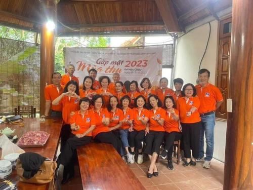um grupo de pessoas em camisas laranja posando para uma foto em The Memory Villa - Mộc Châu em Mộc Châu