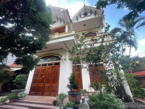 uma casa branca com portas e árvores cor-de-laranja em The Memory Villa - Mộc Châu em Mộc Châu