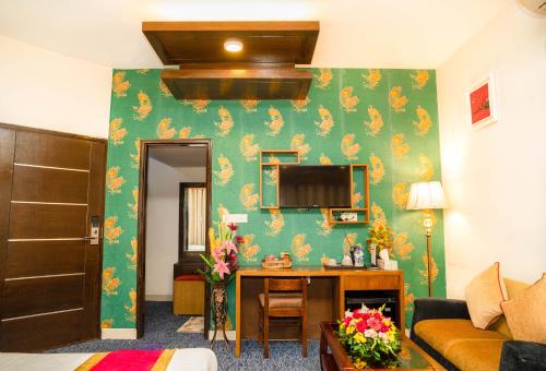 a living room with a green wall with a desk at Hotel Air Inn Ltd - Airport View in Dhaka
