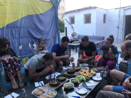 a group of people sitting around a table eating food at Hana hostel in Hurghada