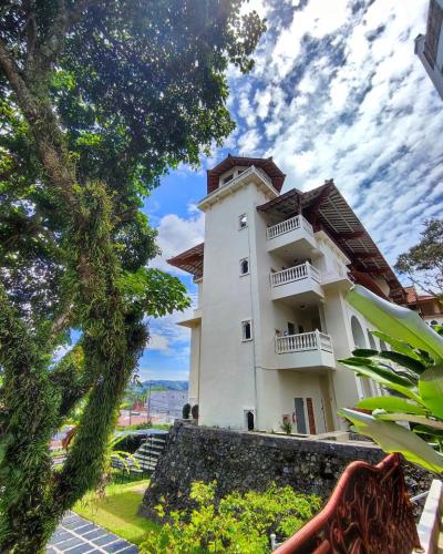 a large white building with balconies and trees at TripleTree Hotel And Resort Bukittinggi in Bukittinggi