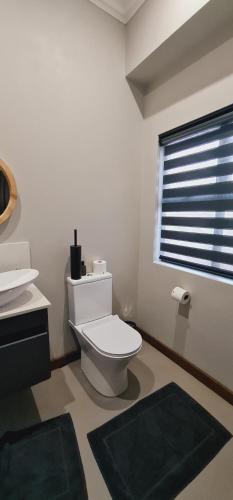 a bathroom with a toilet and a sink and a window at Highland gate Golf estate Mountain view 780 in Dullstroom