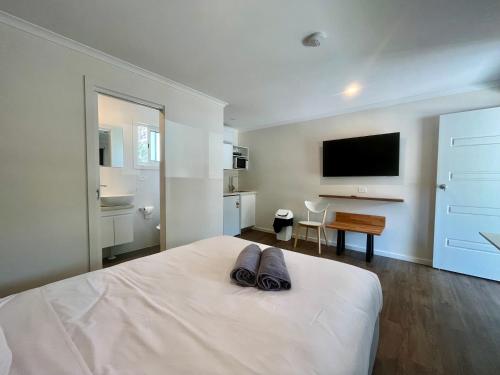 a white bedroom with a bed with a flat screen tv at Young Caravan and Tourist Park in Young