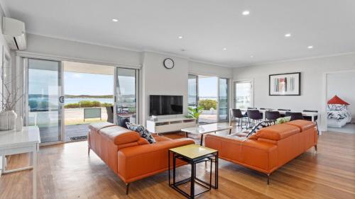 uma sala de estar com dois sofás laranja e uma televisão em Beachview em Coffin Bay
