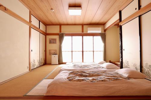 a bedroom with three beds in a room with a large window at Osaka Umeda Yuan Hostel in Osaka