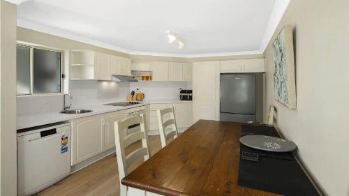 a kitchen with a wooden table and a wooden floor at Summer By The Sea Umina Beach in Ettalong Beach