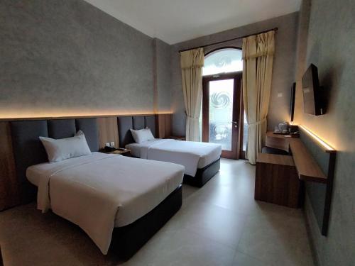um quarto de hotel com duas camas e uma janela em The Grand Palace Hotel Malang em Malang