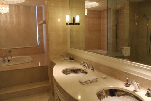 a bathroom with a sink and a mirror and a tub at Ramada Plaza Weifang in Weifang
