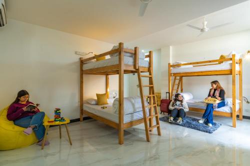 two girls sitting in a room with bunk beds at The Social Stays Dehradun Previously ArtBuzz in Dehradun