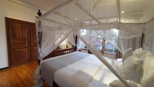 a bedroom with a bed with a canopy at Margaret House in Mirissa
