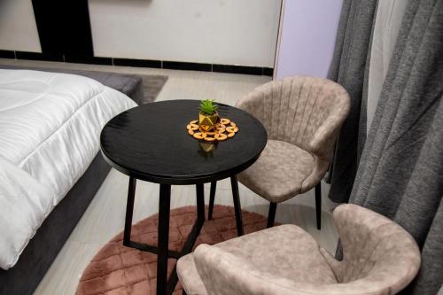 a table with two chairs and a plant on it at BryMac Hotel in Koforidua