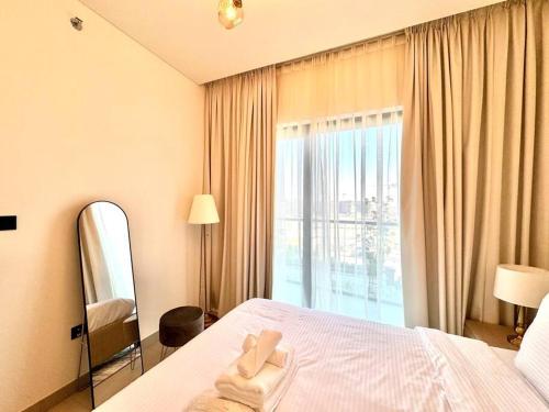 a bedroom with a bed with a mirror and a window at Stylish brand new 1 bedroom in Dubai