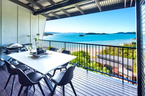 a table and chairs on a balcony with a view of the ocean at Panorama 4 & Free Buggy - Hamilton Island in Hamilton Island