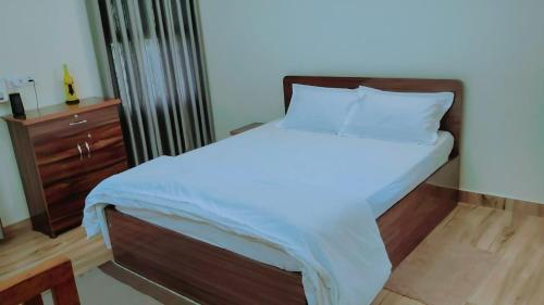 um quarto com uma cama grande com lençóis brancos e uma cómoda em The ROI Palace em Faridabad