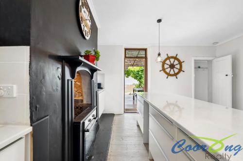 cocina con encimera y reloj en la pared en Hyde Cottage, en Meningie