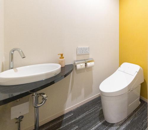 a bathroom with a white toilet and a sink at The Hotel Obuse in Obuse