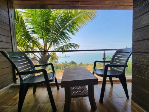 2 sillas y una mesa frente a una ventana en Ocean Front By Seascapes en Ānjarle