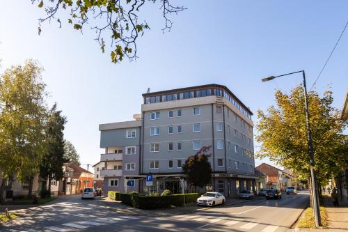 ein hohes graues Gebäude in einer Stadtstraße mit geparkten Autos in der Unterkunft Art Hotel in Slavonski Brod