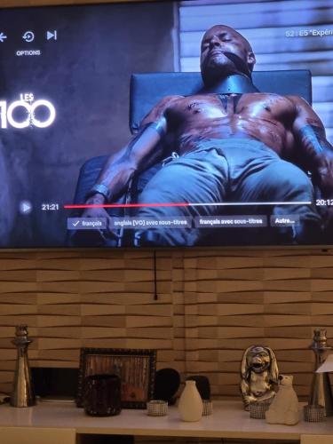 une télévision avec une photo d'un homme à l'écran dans l'établissement Appartement La Garenne Jacuzzi et Balcon à 15 min de Paris JO 2024 et Stade de France TARIFS PRIVILEGES SEMAINE OU MOIS DISPONIBLE, à Franconville