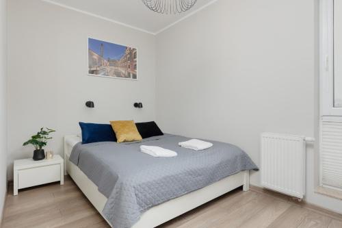 um quarto branco com uma cama com almofadas azuis e amarelas em Modern One Bedroom Apartment with Parking in Łódź by Renters Prestige em Lódź