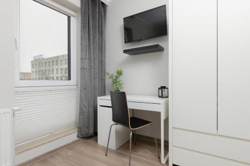 uma secretária branca com uma cadeira e uma televisão na parede em Modern One Bedroom Apartment with Parking in Łódź by Renters Prestige em Lódź