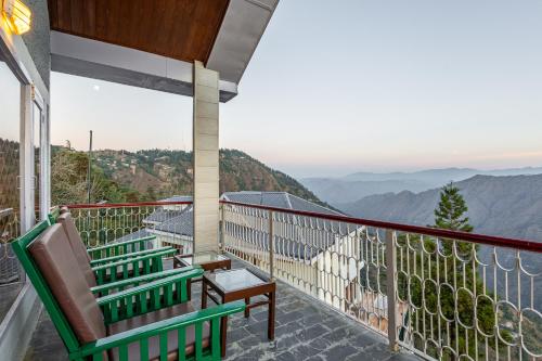 a balcony with two chairs and a view of mountains at Breezedale in Shimla