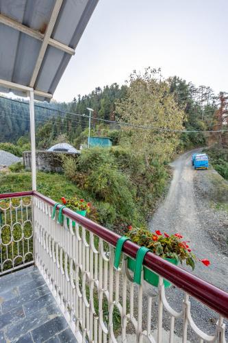 a balcony with a white fence and flowers on a road at Breezedale in Shimla