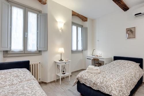 een slaapkamer met 2 bedden, een bureau en ramen bij Oltrarno Dreaming in Florence