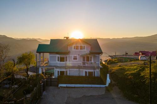 a house with the sun setting on top of it at Breezedale in Shimla
